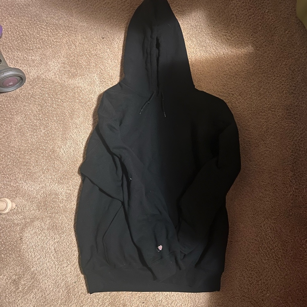 Plain black hoodie with a “c” and a heart on the sleeve